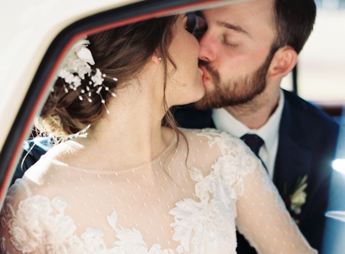 bride and groom kissing in the vintage getaway car