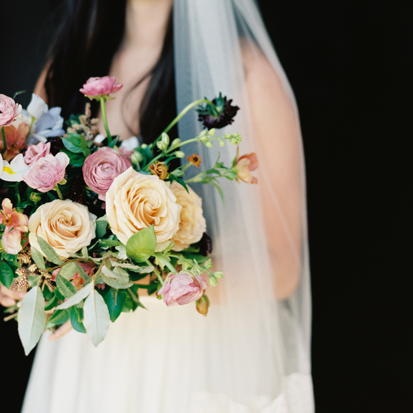 lush floral inspiration for bridal bouquet with bride on dark background with long veil and silk strapless wedding gown