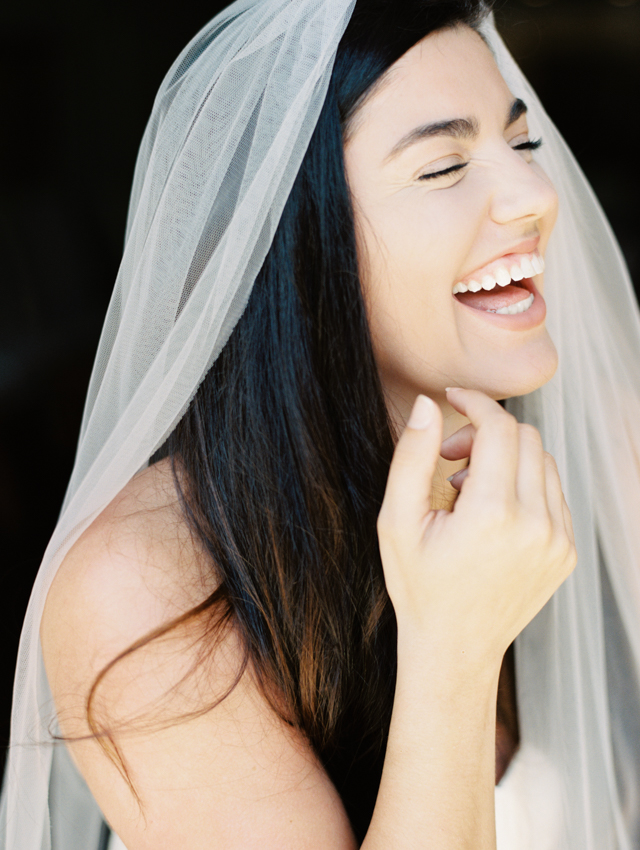 classic, laughing candid image of the bride with long veil and strapless silk wedding dress